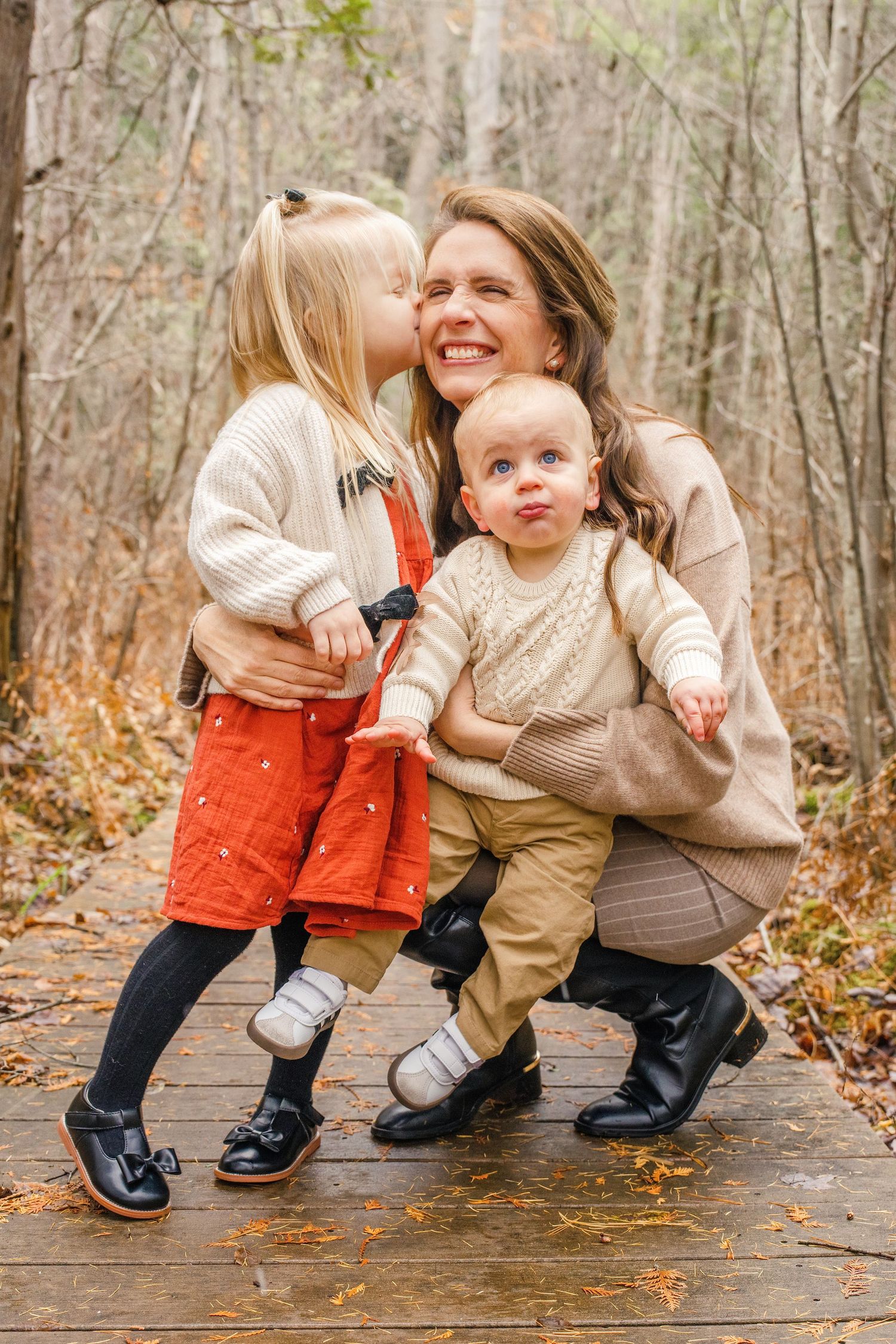 Three candid photos show a tender moment between two people crouching on a wooden boardwalk in autumn.