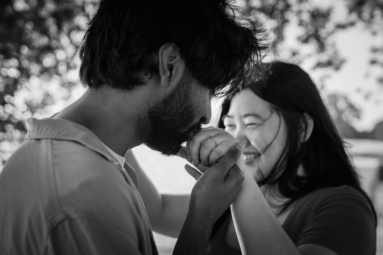 A tender black and white romantic moment between a couple sharing laughter outdoors.