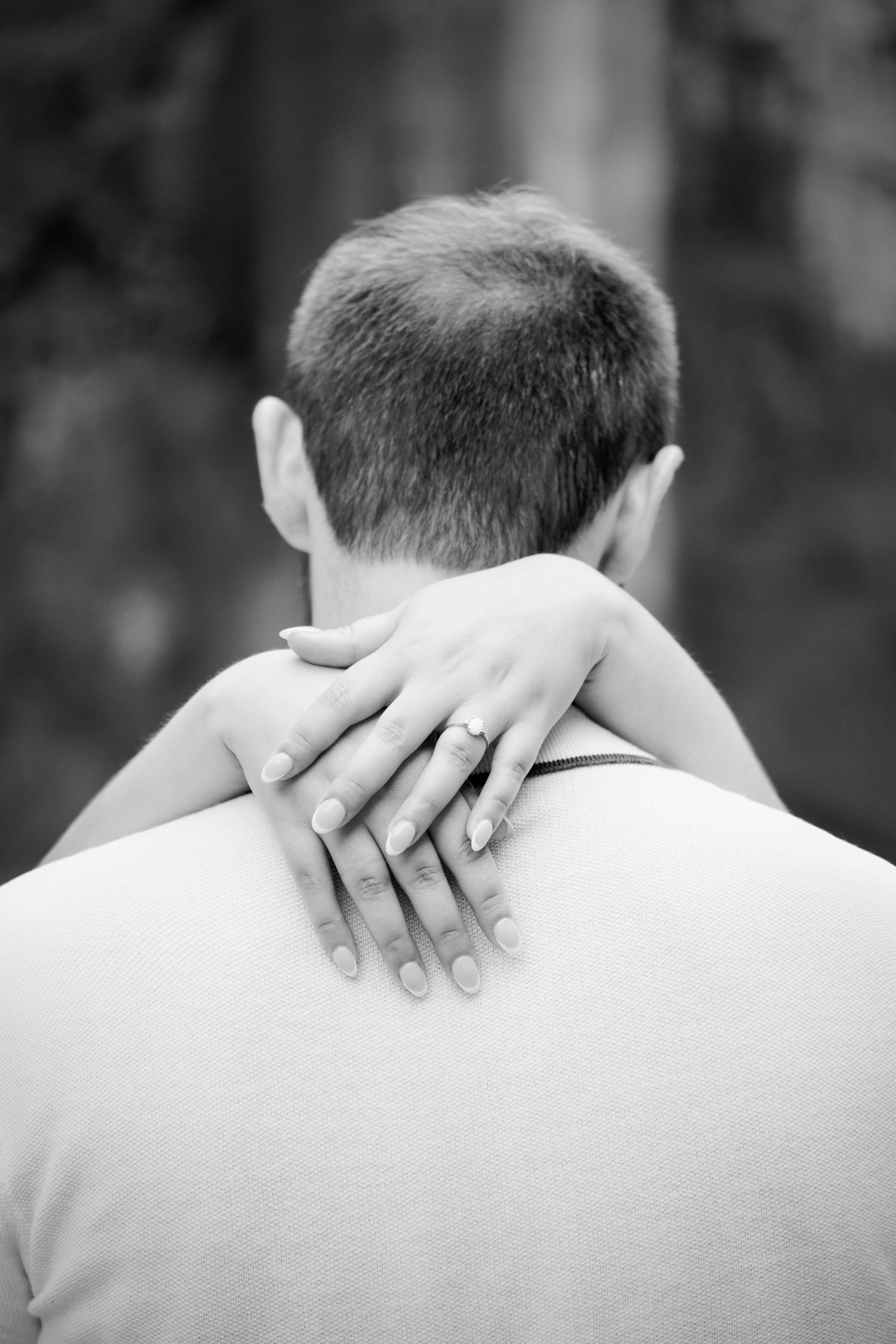 Close-up black and white photo showing hands gently resting on the back of a white shirt.