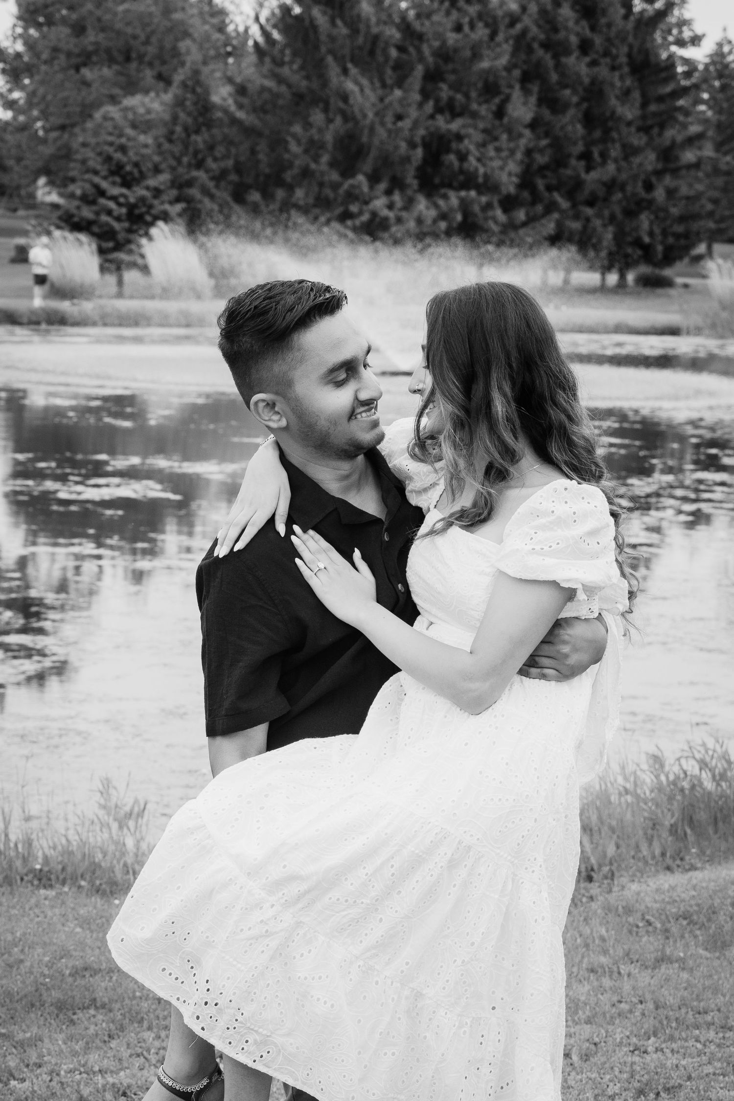 Couple shares tender moments in a series of black and white photos near a pond.