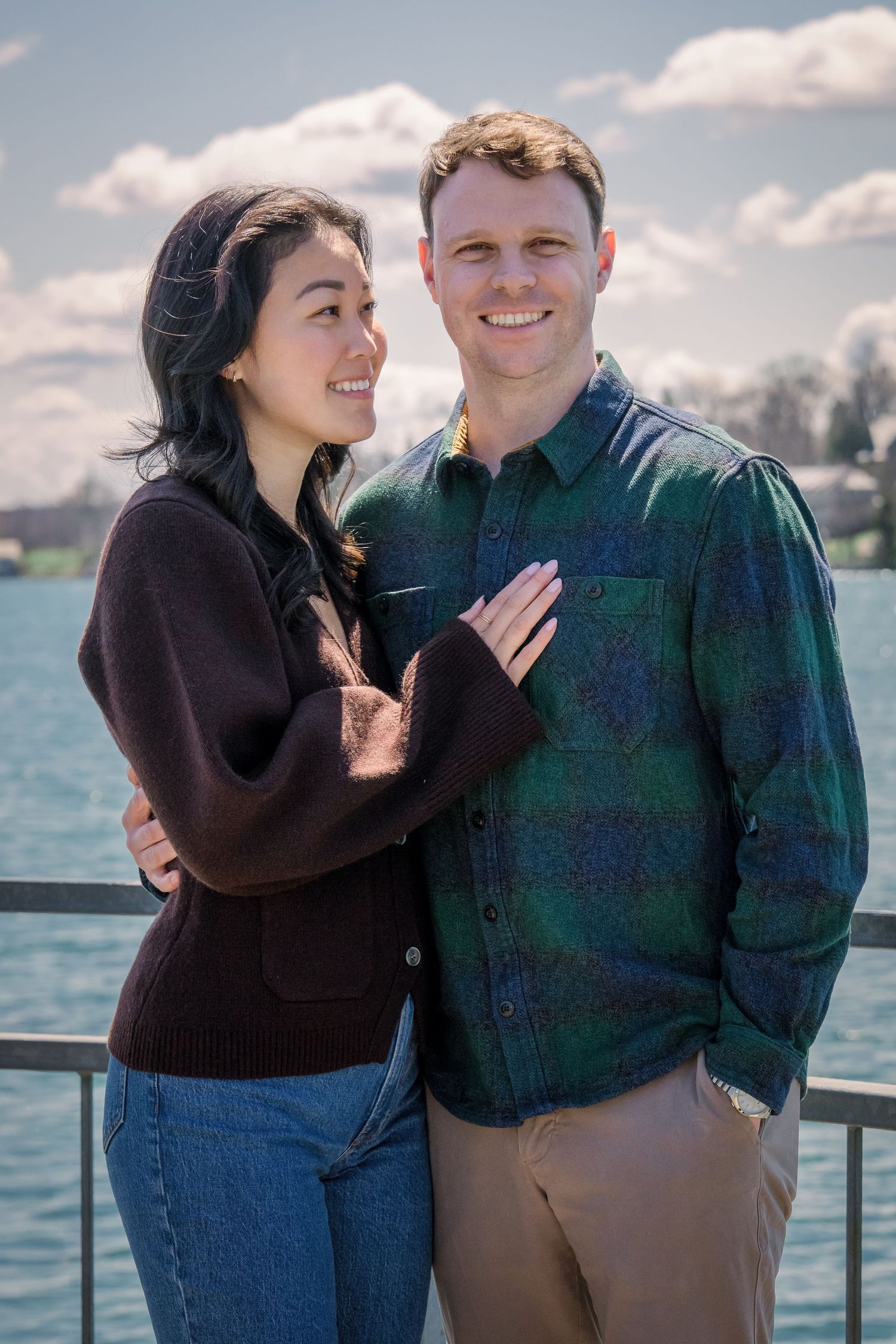 A happy couple sharing joyful moments together by the waterfront on a sunny day.