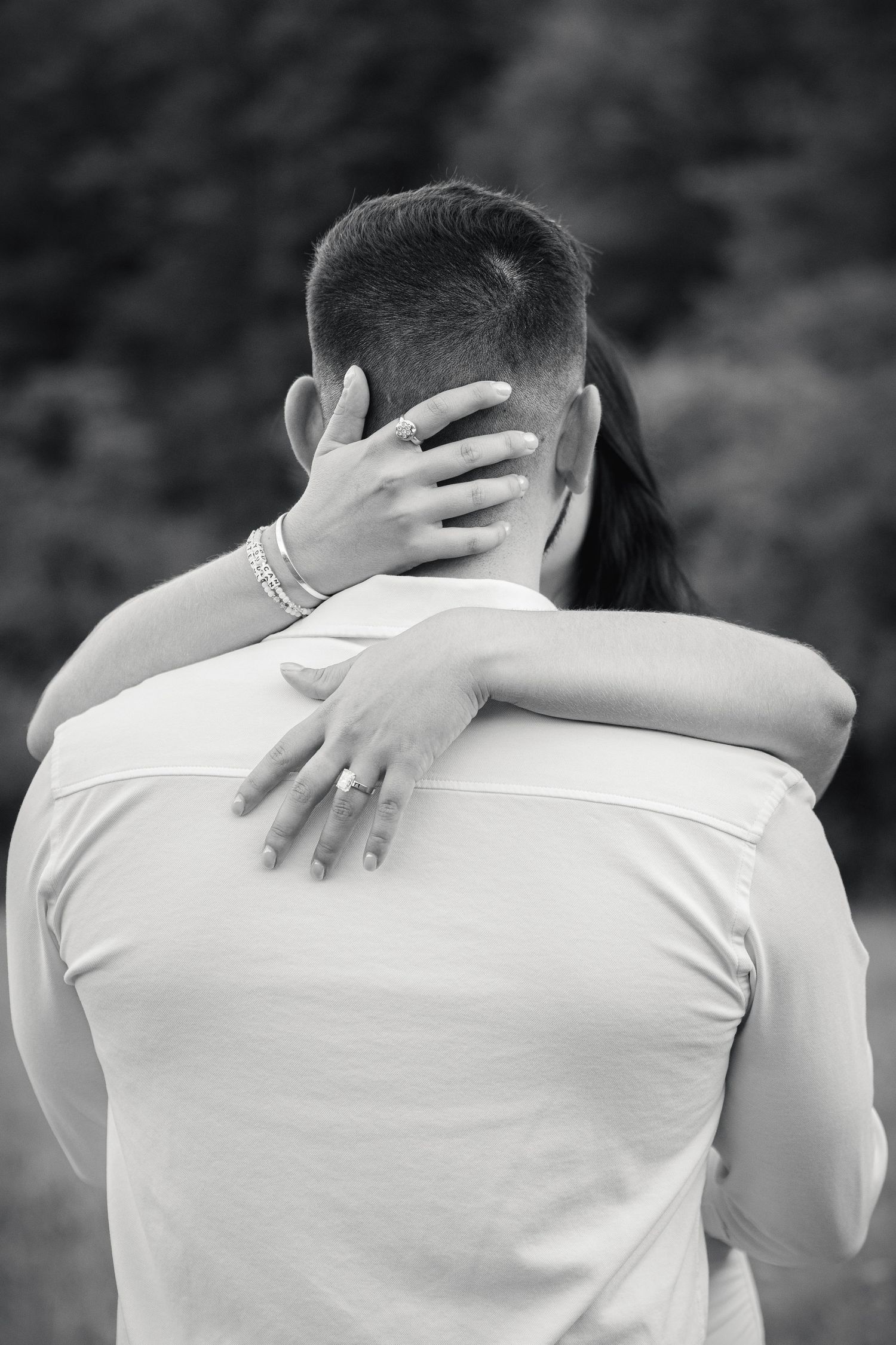 A close-up black and white photo showing an intimate embrace with hands wrapped around each other.