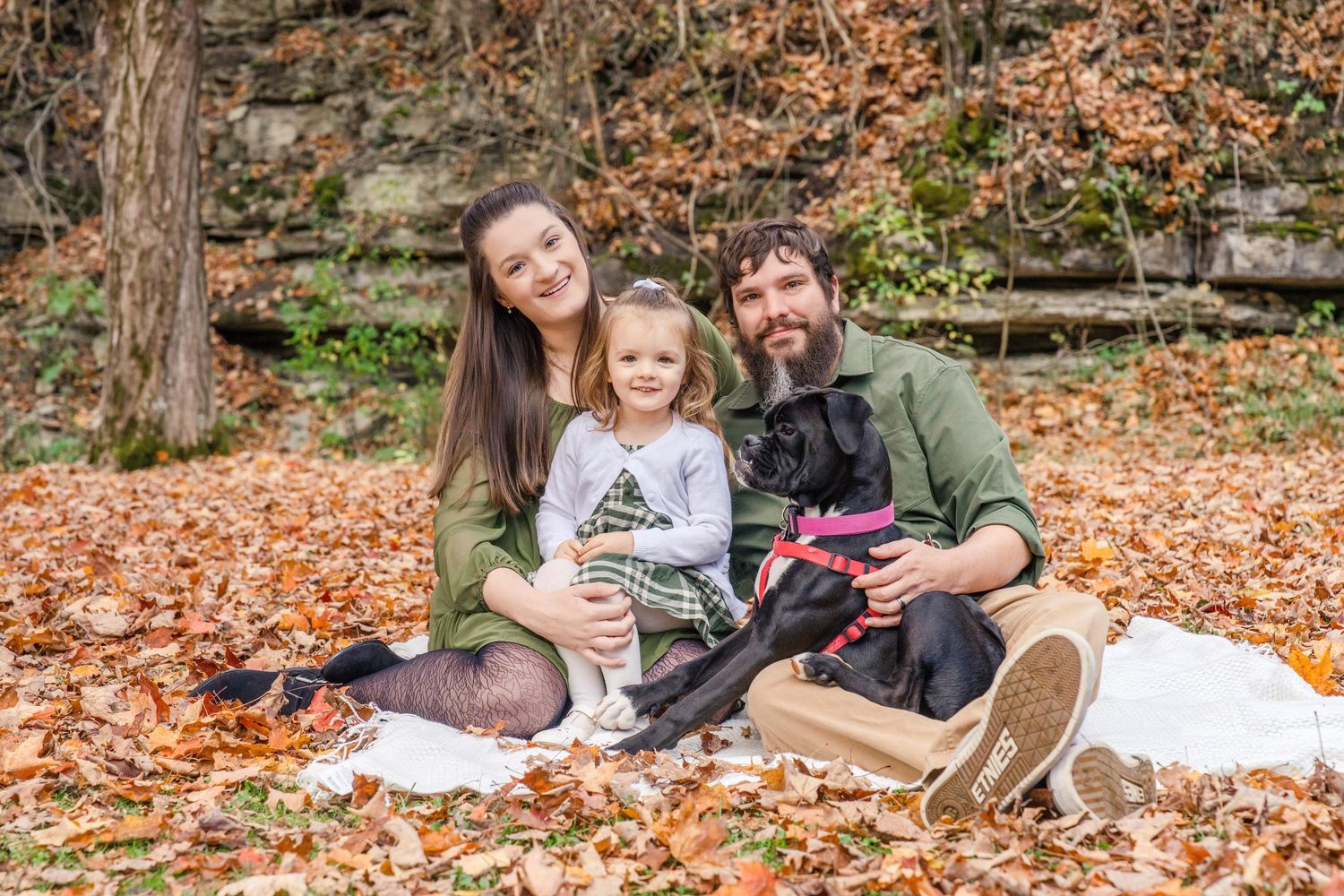 Family enjoying a cozy autumn picnic together on fallen leaves in a park setting.