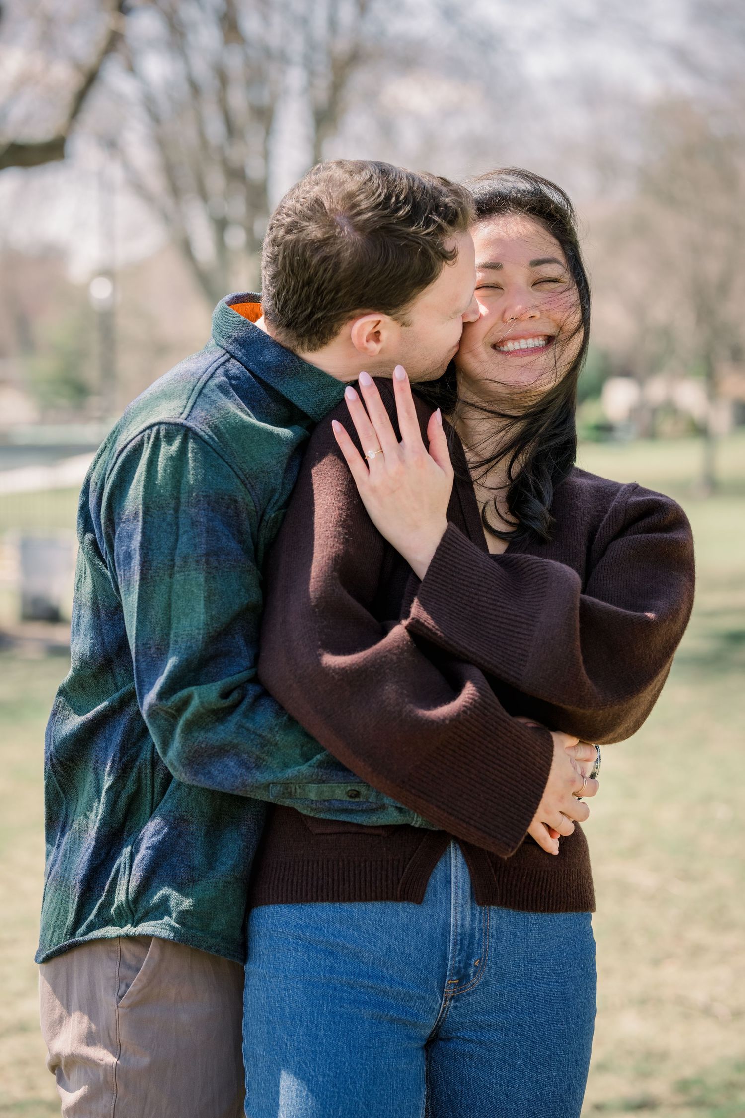 A romantic photoshoot capturing candid moments of affection in a park setting.