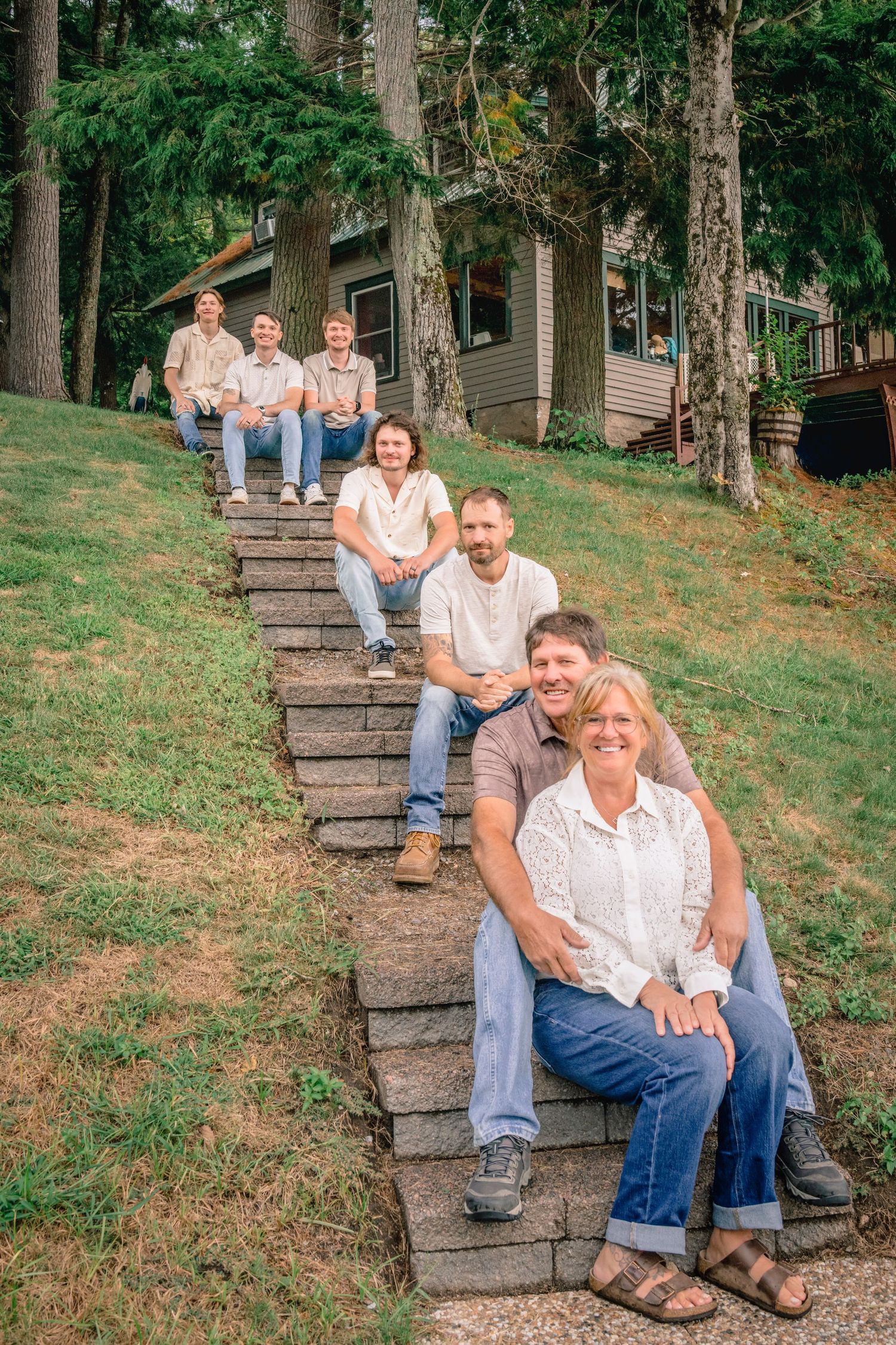 Group relaxes together on outdoor stone steps surrounded by trees and greenery.