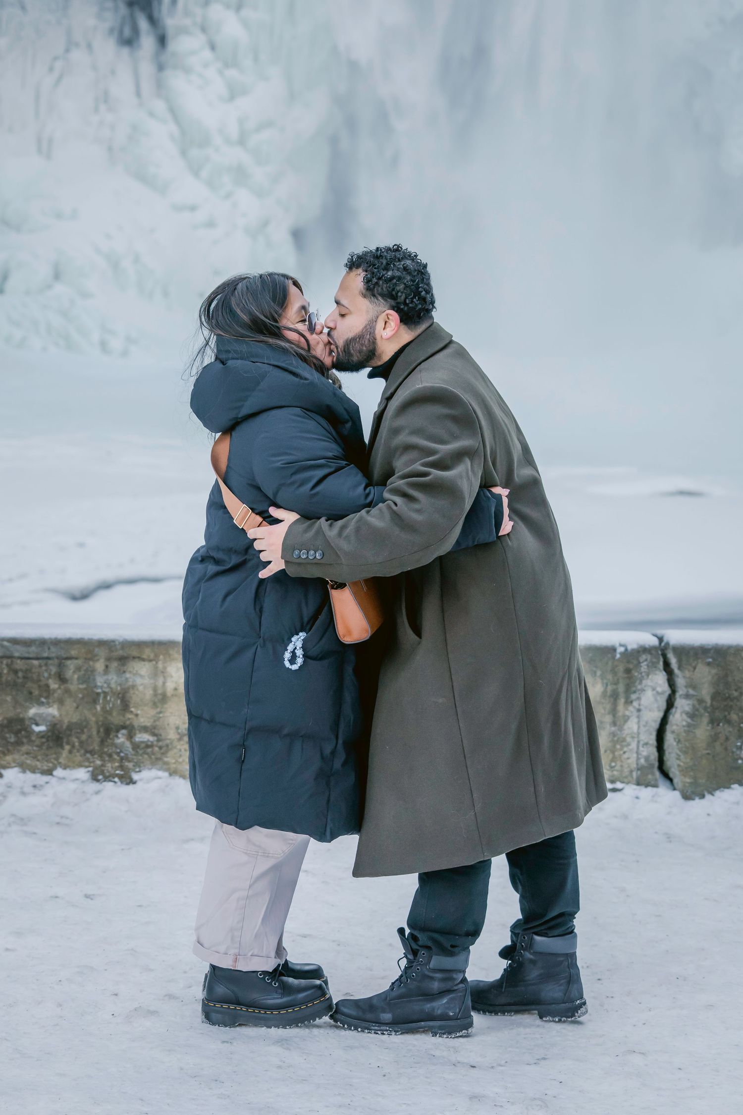 Two people share an intimate moment while kneeling in the snow on a winter day.