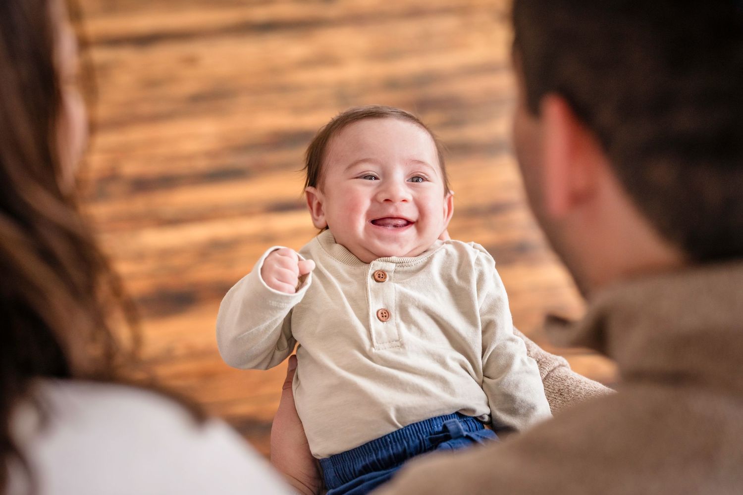 A sequence of candid shots showing a baby laughing and smiling while interacting with someone off camera. Family photos.