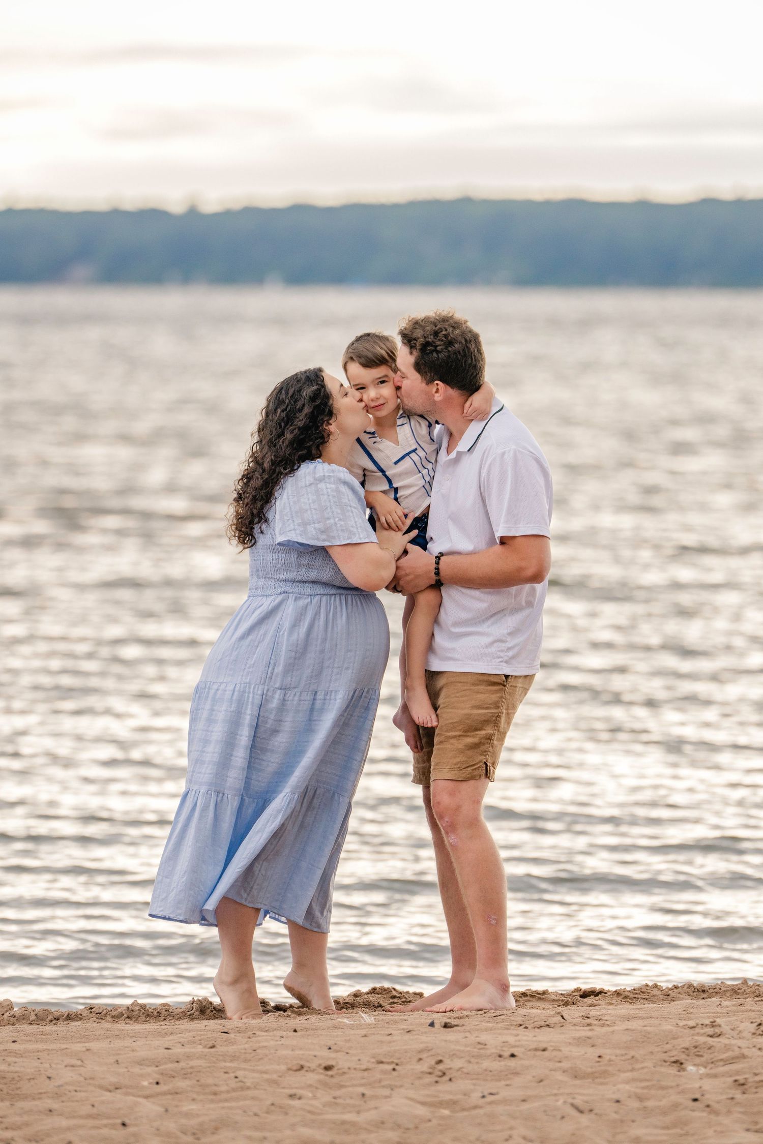 A family spends quality time together on a beach at sunset with water in the background.
