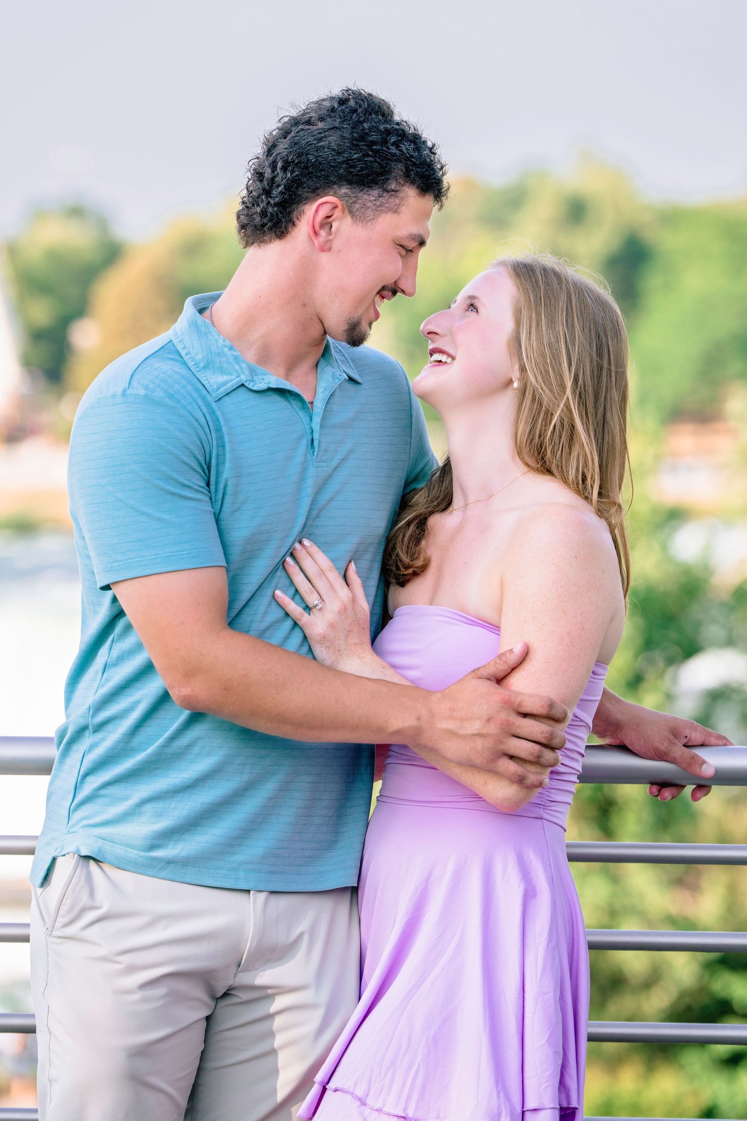 A romantic couple in blue and purple outfits embraces against a scenic backdrop.