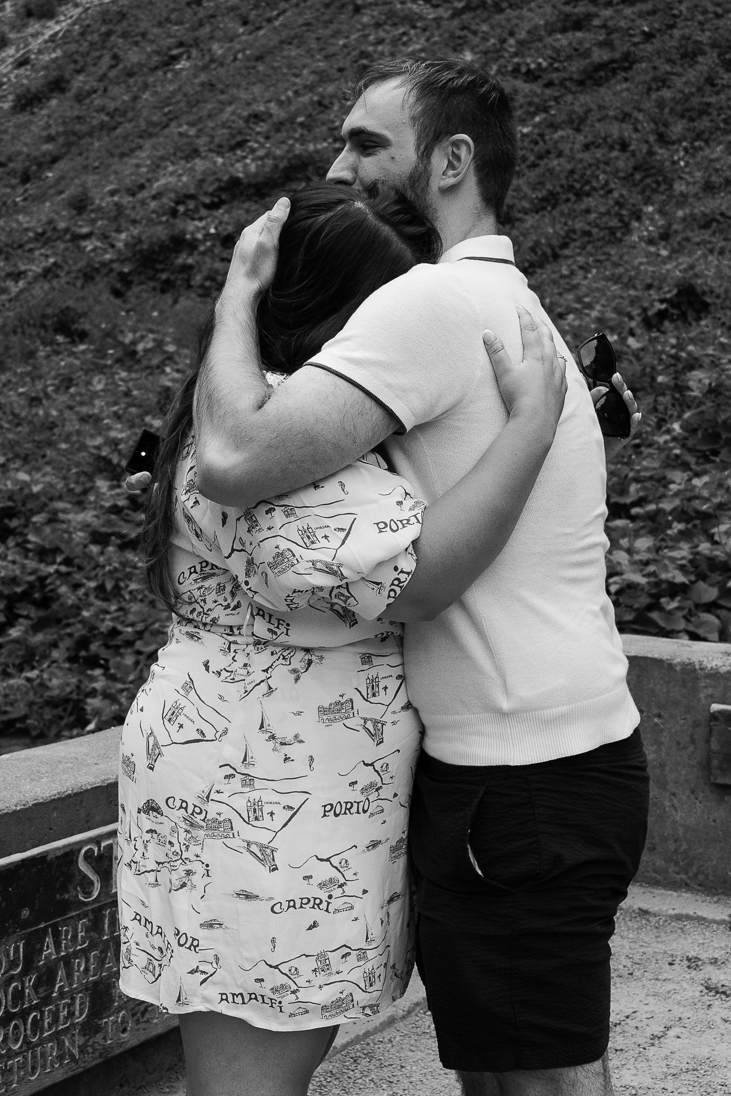 A sequence of black and white photos showing two people embracing while standing outdoors on a path.