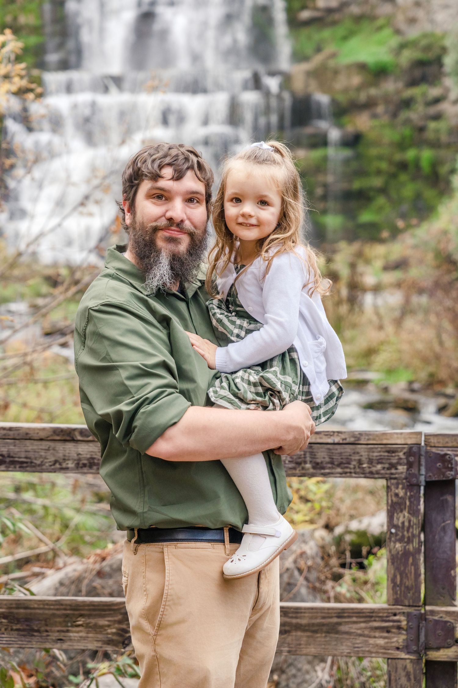 Two people share a joyful moment together while posing near a scenic waterfall in the background.