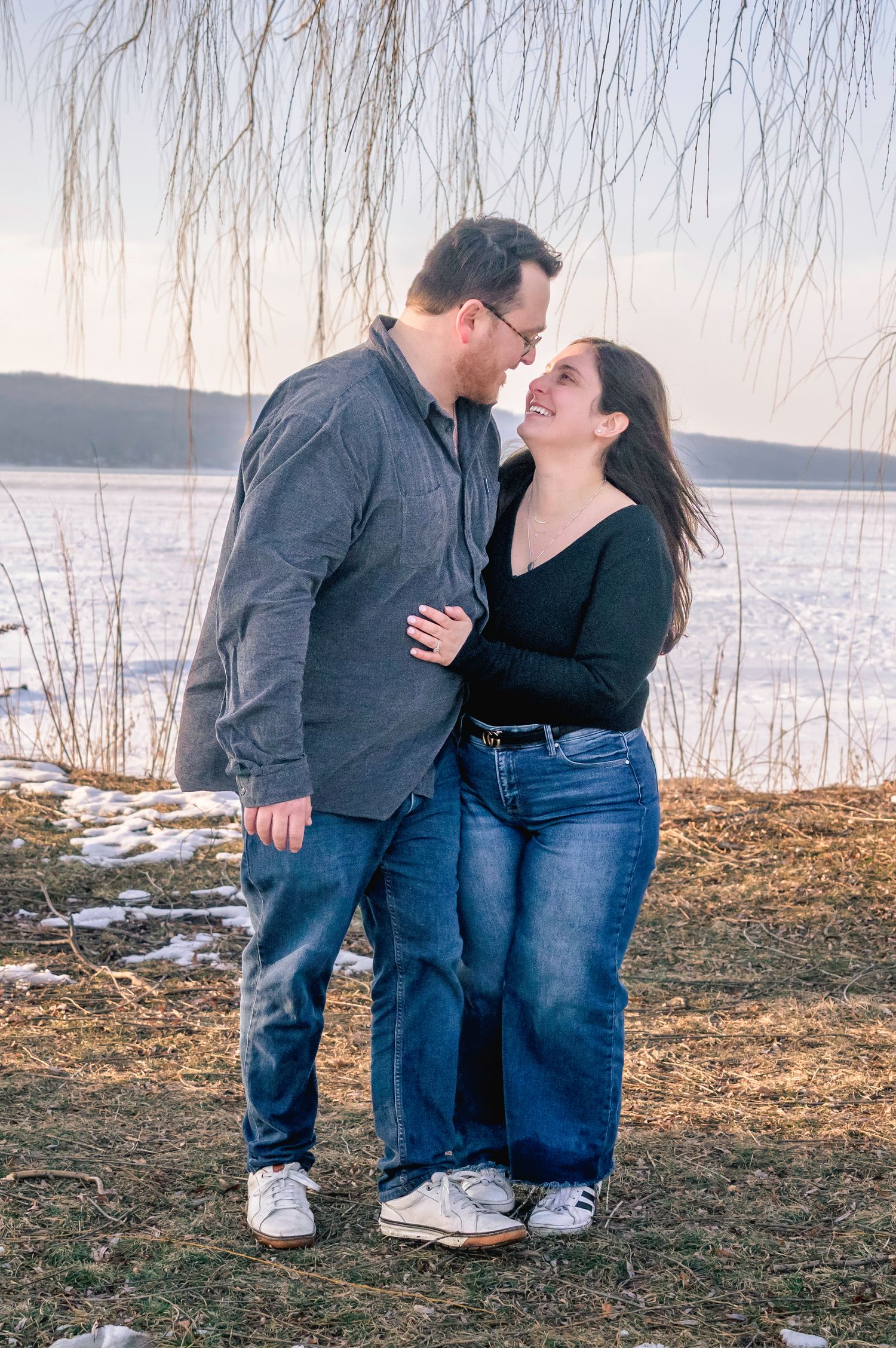 Romantic couple gazing at each other near a frozen lake in winter landscape.