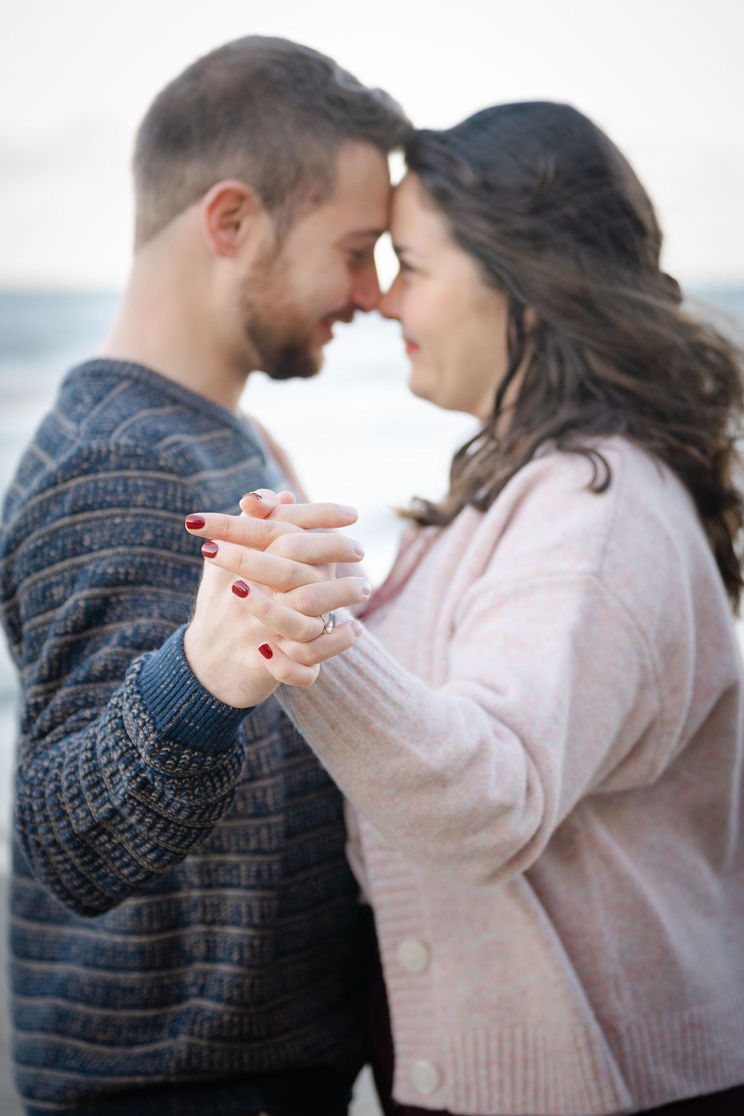 A romantic couple in cozy sweaters dancing together in a series of intimate poses against a light background.