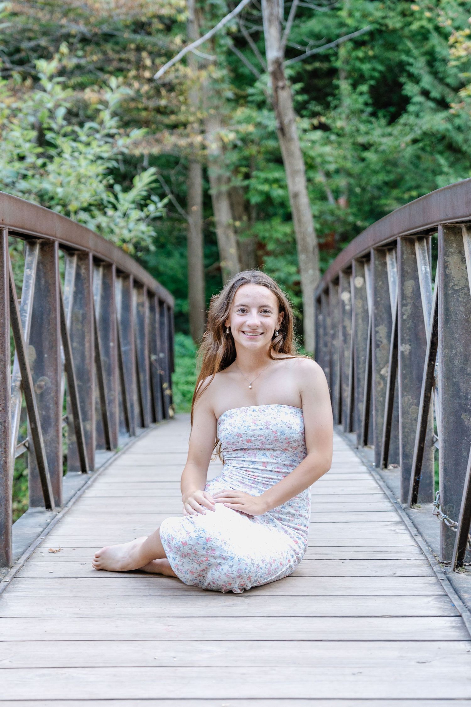 A strapless white dress on a rustic wooden footbridge surrounded by lush green forest.