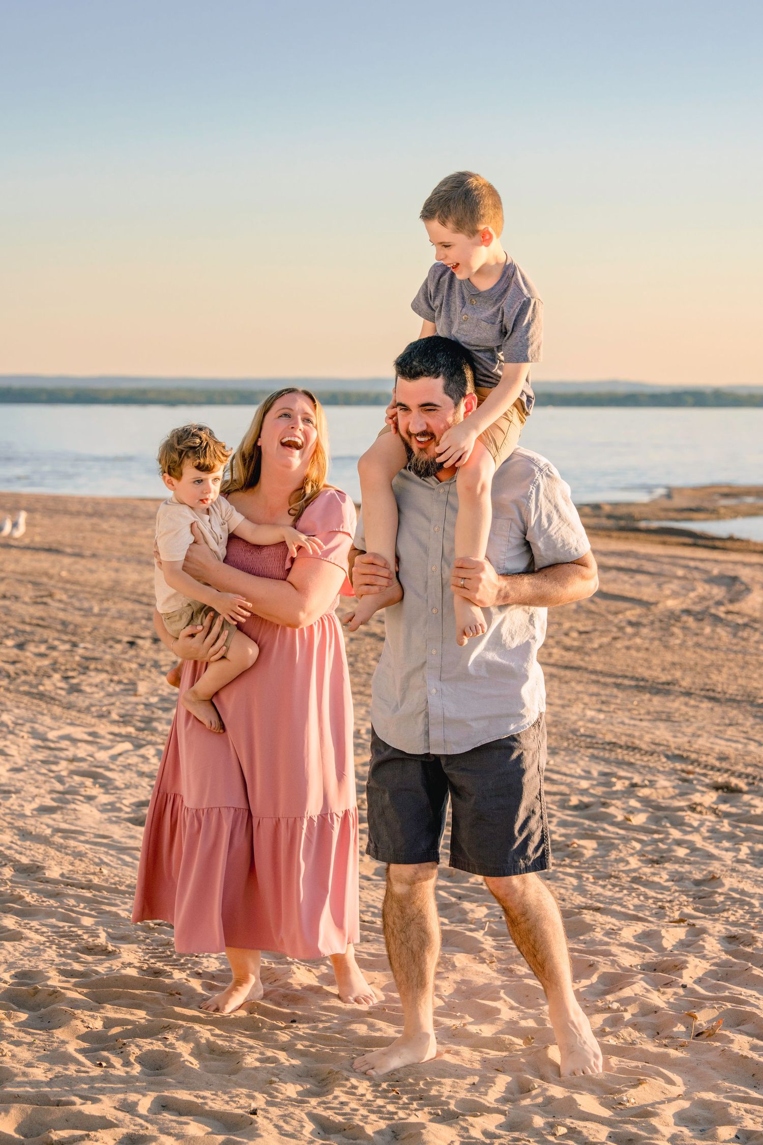 A family plays together on a sandy beach during golden hour, creating joyful moments at sunset.