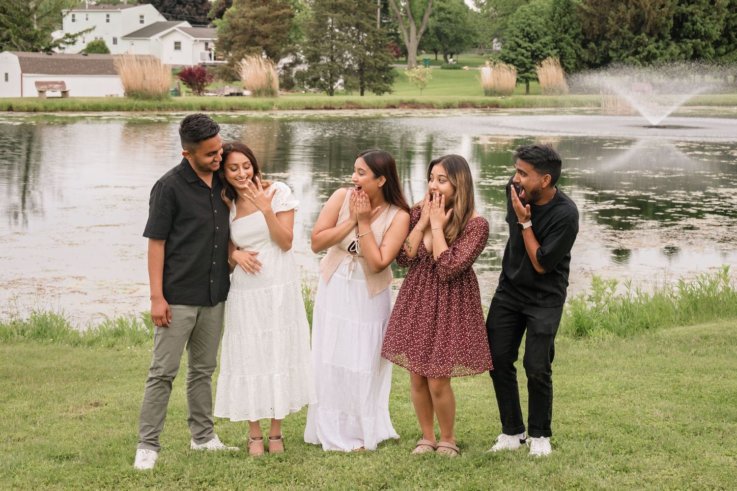 A romantic celebration scene by a lake with friends in the background.
