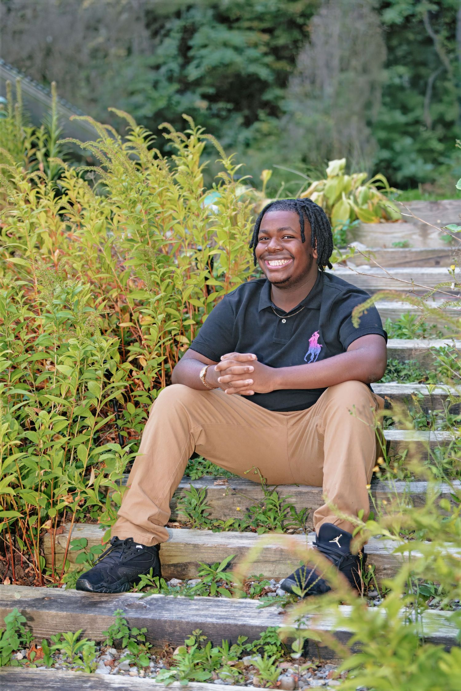 Person relaxes on concrete steps surrounded by lush greenery and yellow wildflowers in natural setting.