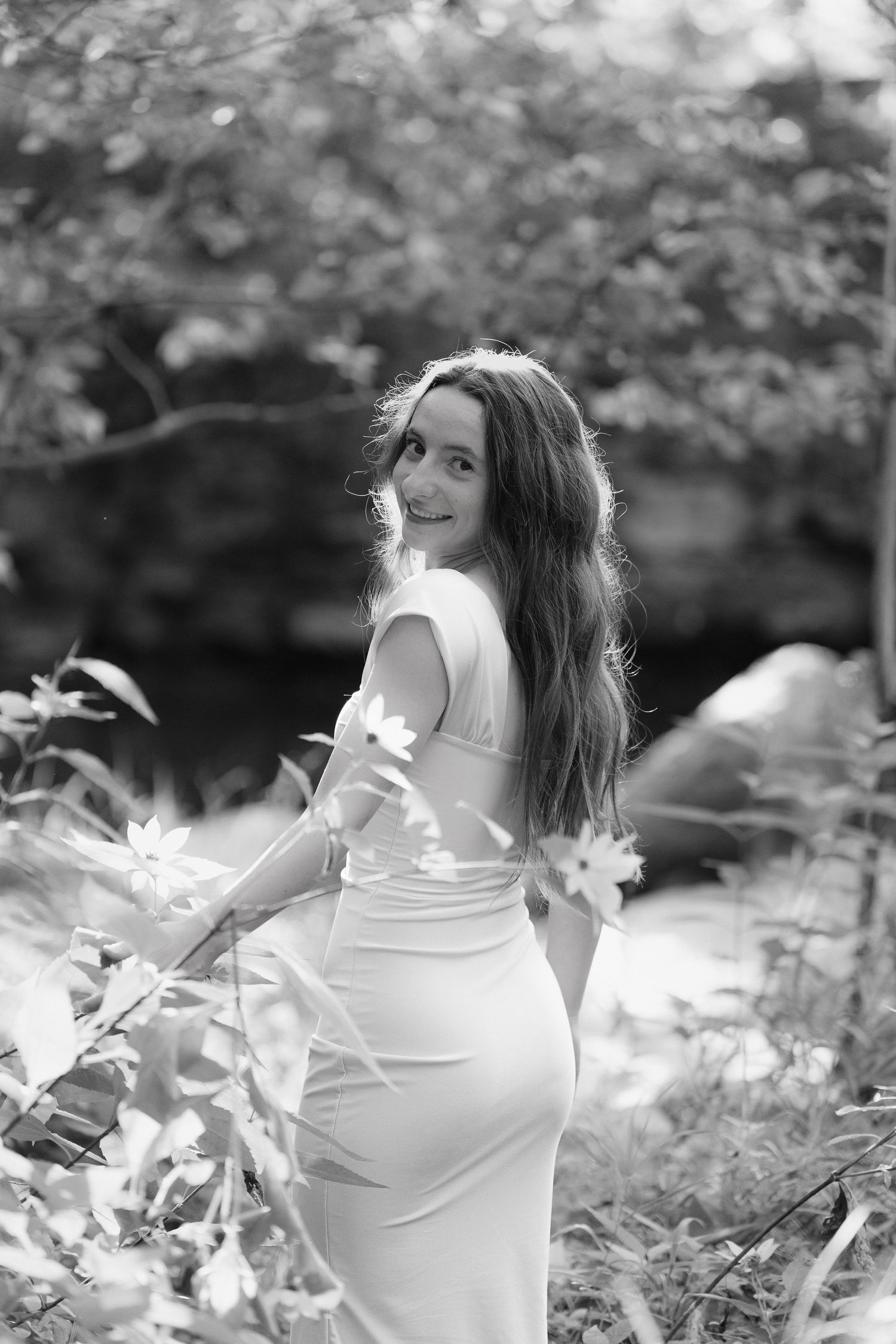 Black and white artistic portrait series showing a woman in a white top among flowers in a dreamy garden setting.