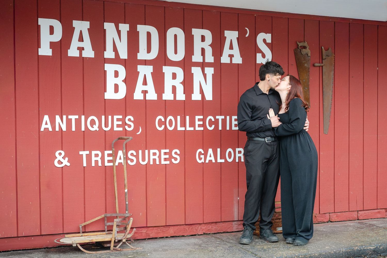 Couple kissing in front of Pandoras Barn antiques and collectibles red barn store exterior.