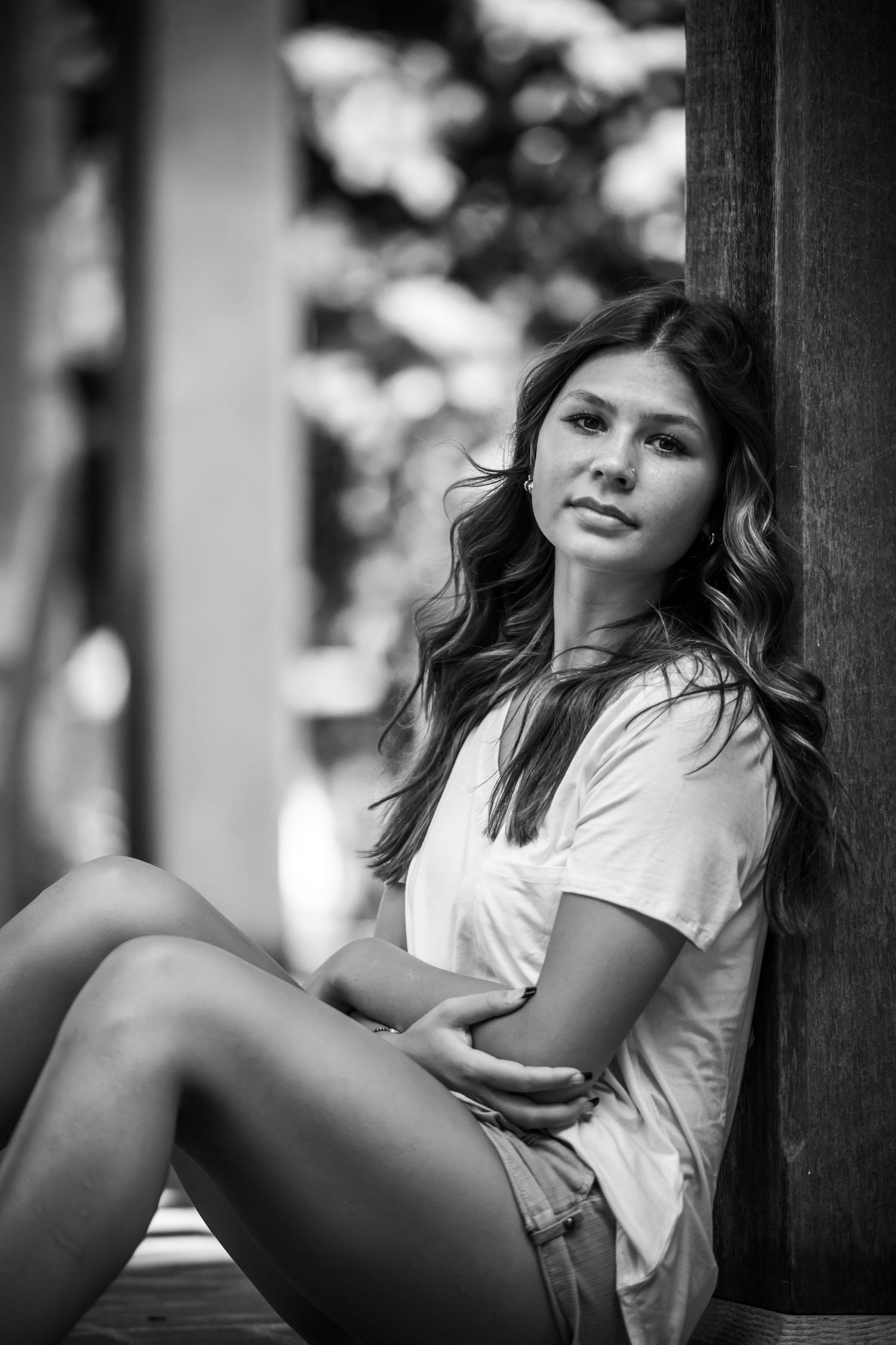 Black and white portrait against column with artistic lighting and shadows.