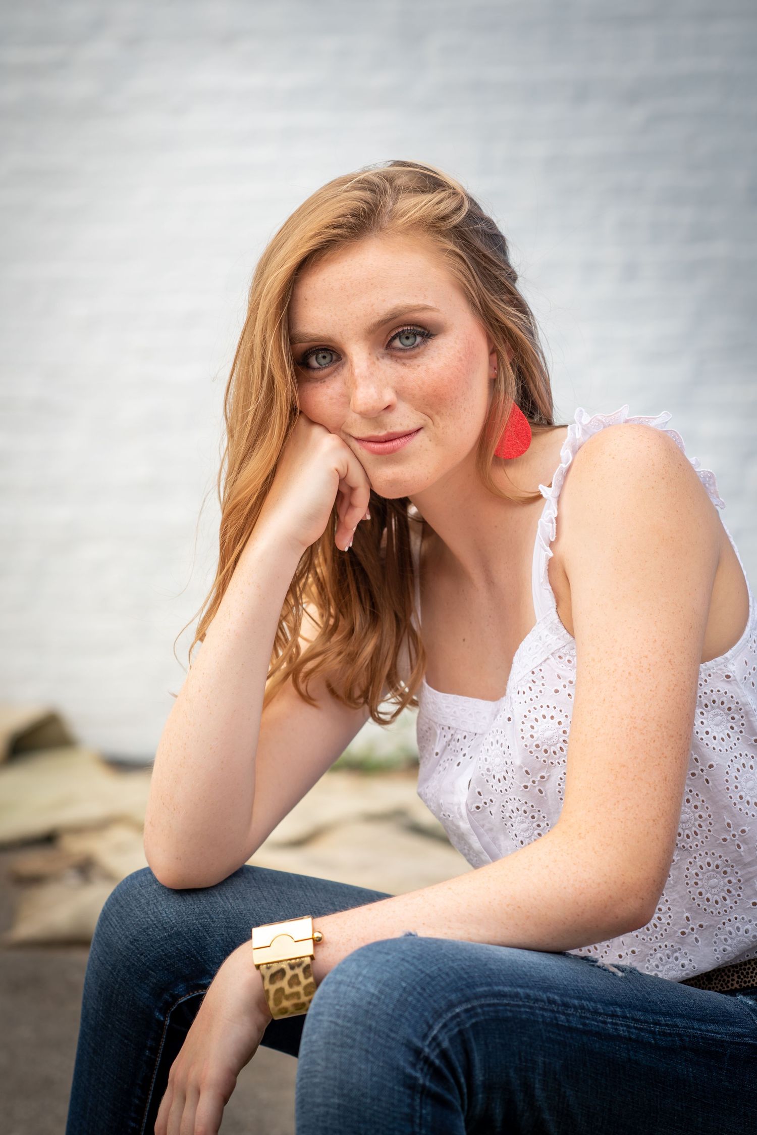 Portrait featuring red statement earrings and white eyelet top in natural lighting.