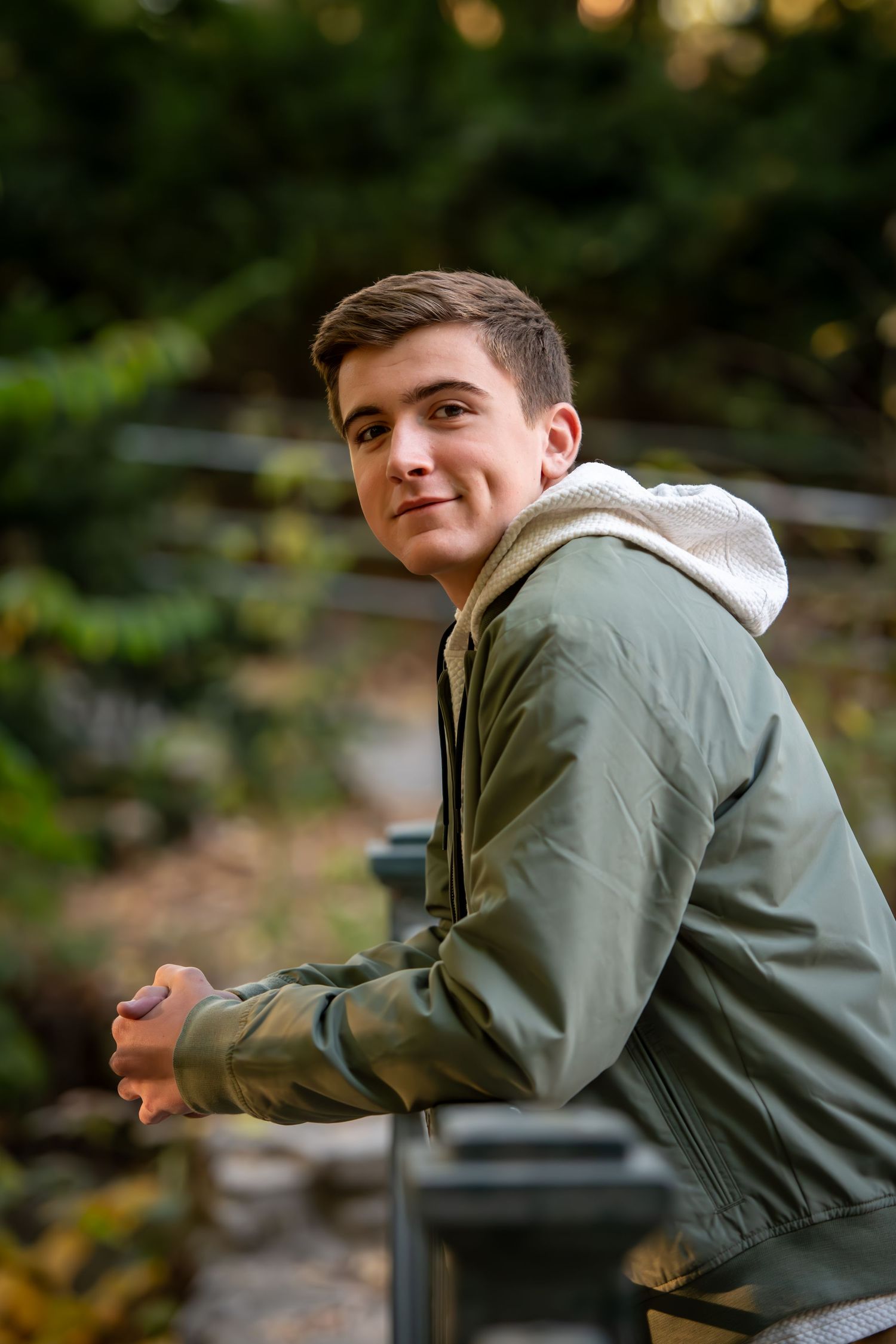 Casual outdoor portrait in olive green hoodie jacket against natural forest background.