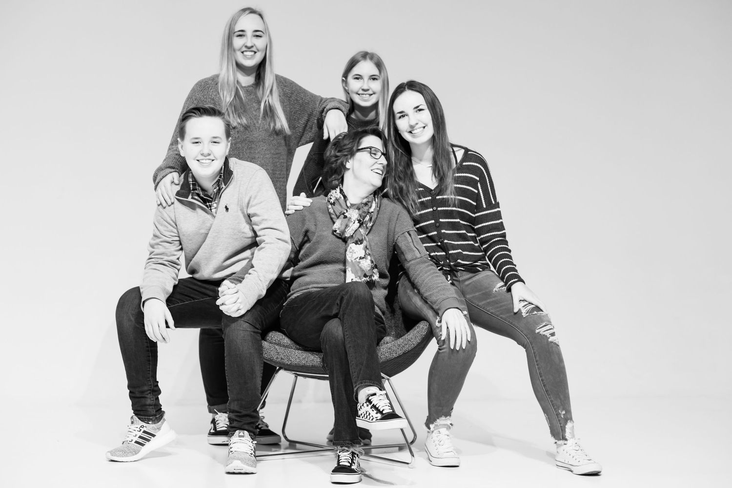 Modern family group shot posed casually together in black and white studio portrait in Overland Park, KS