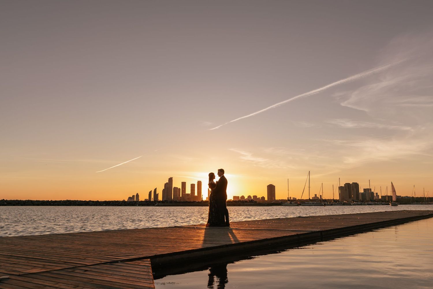Panoramic sequence of a silhouetted couple walking along a wooden pier at sunset with serene ocean views.