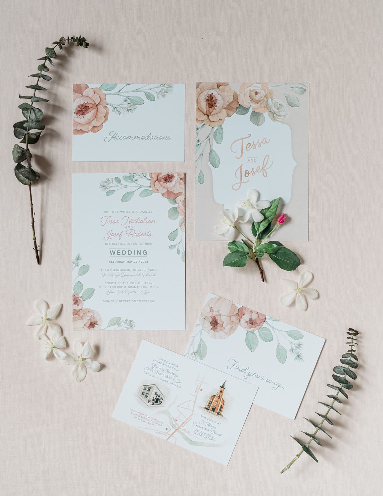 Elegant wedding invitation suite in soft blue and peach floral design with eucalyptus sprigs and white flower petals.