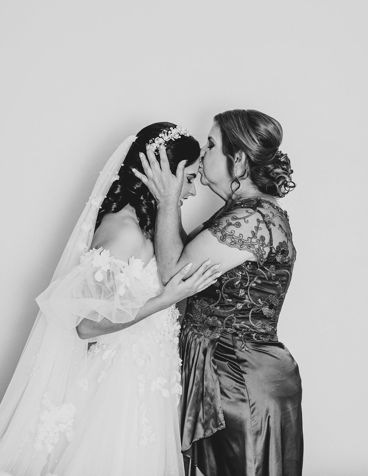 A tender moment between a bride in white and companion in black lace during an intimate wedding portrait.