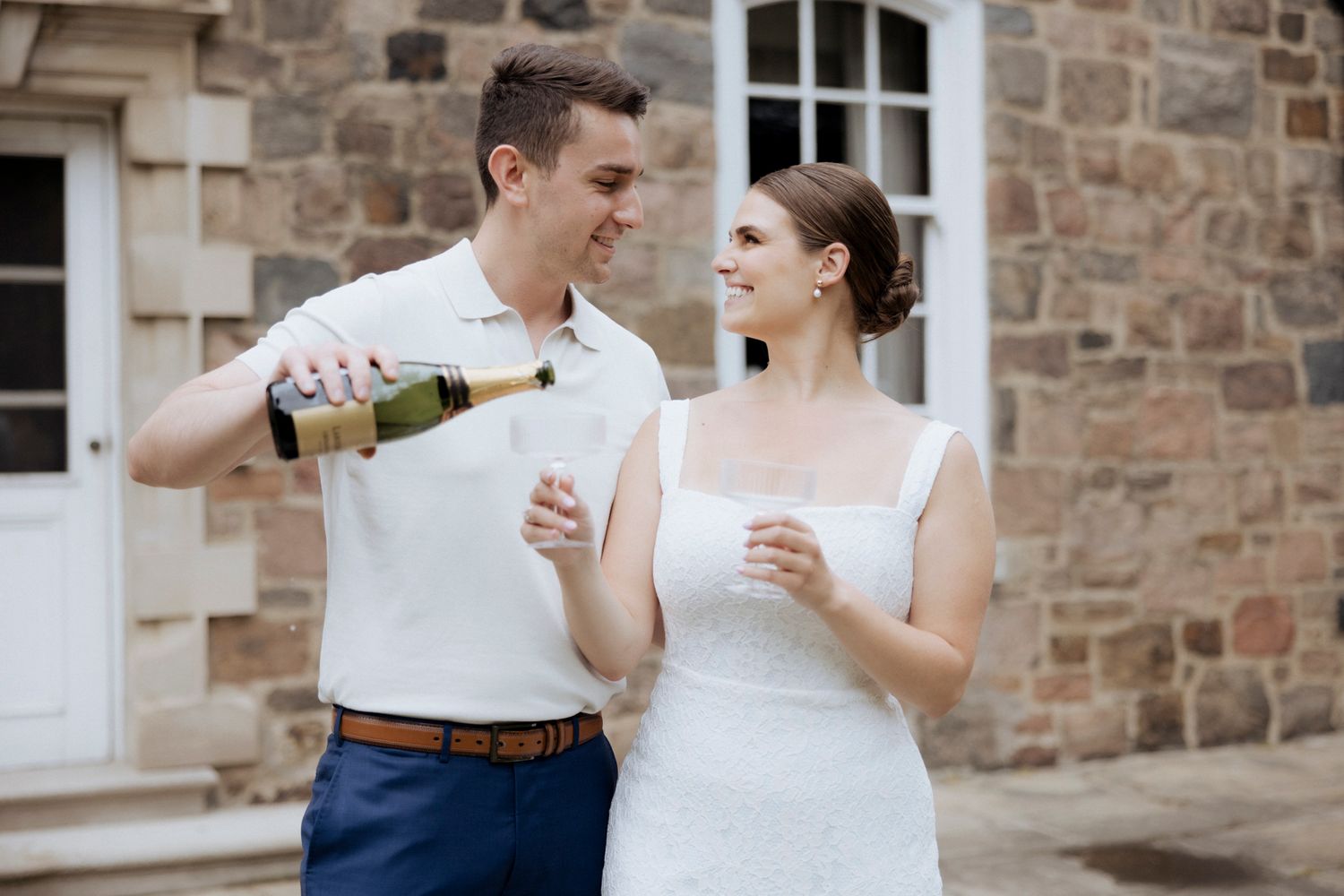 A celebratory moment as champagne is poured outside a stone building.