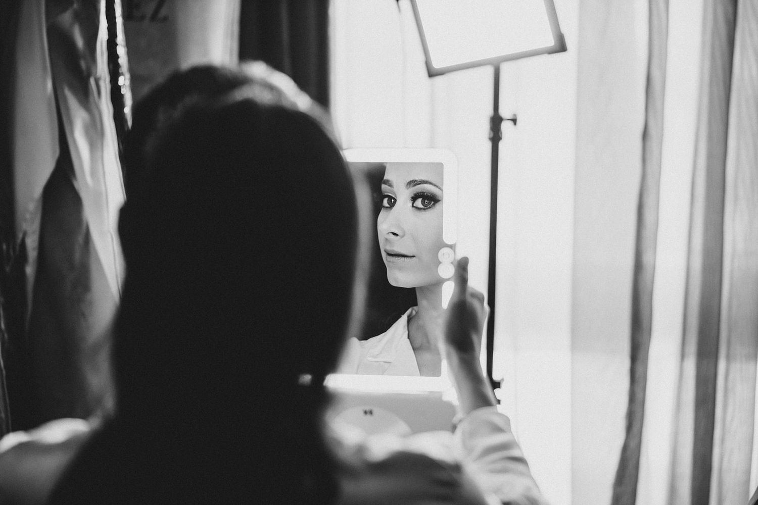 A black and white photo showing a person looking at their reflection in a mirror.