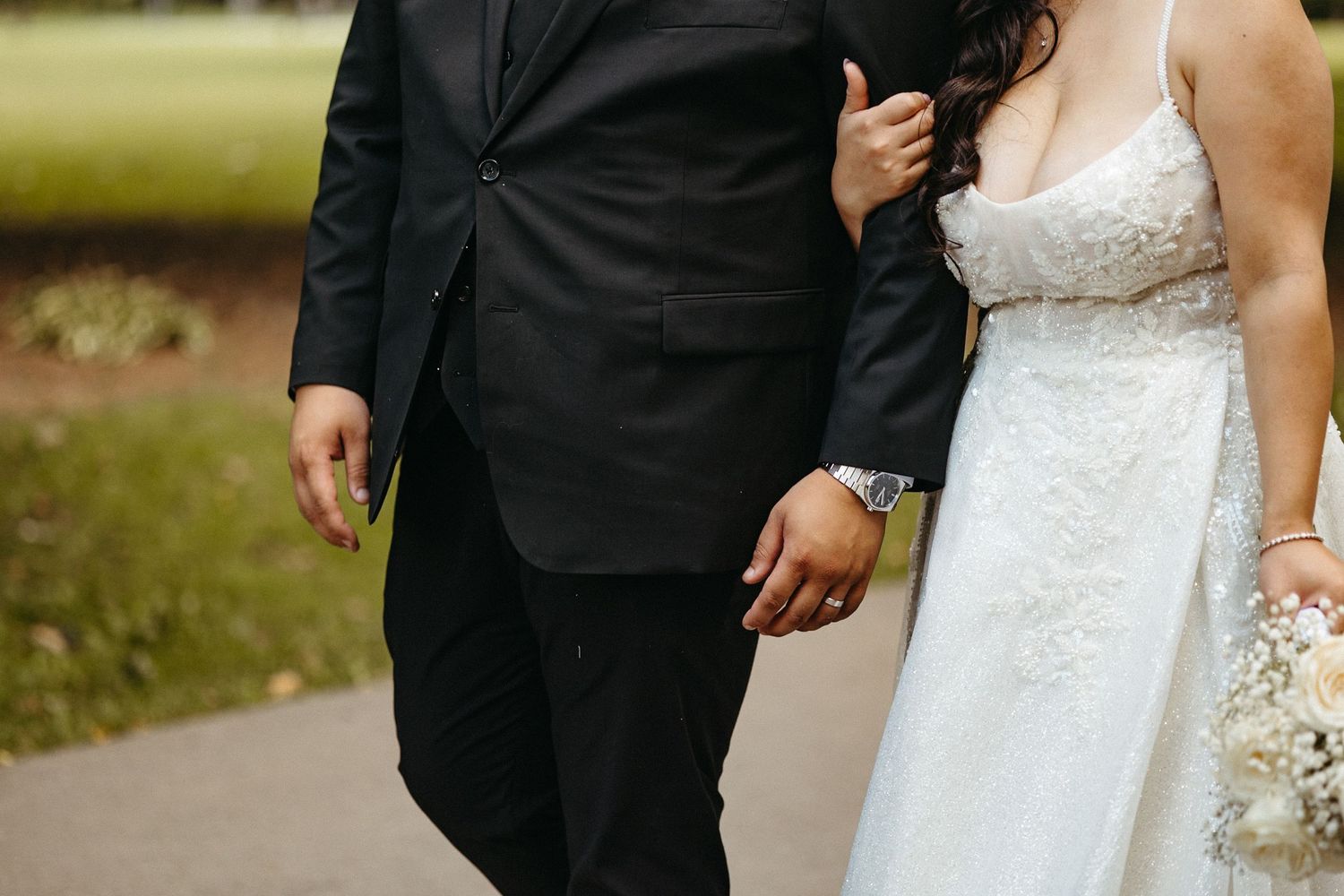 Wedding couple walking together outdoors showing formal attire details.
