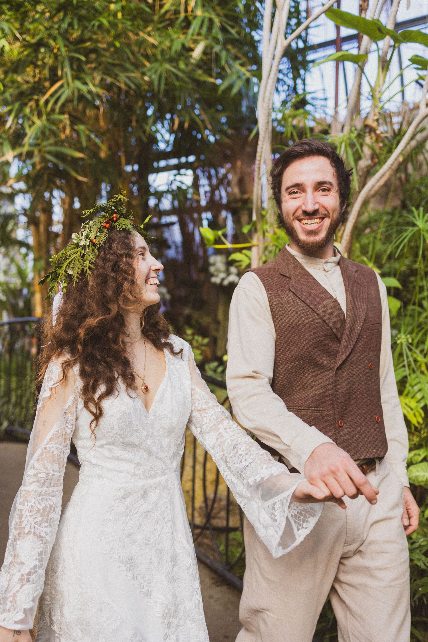 A couple at an outdoor wedding celebration surrounded by tropical plants and greenery.