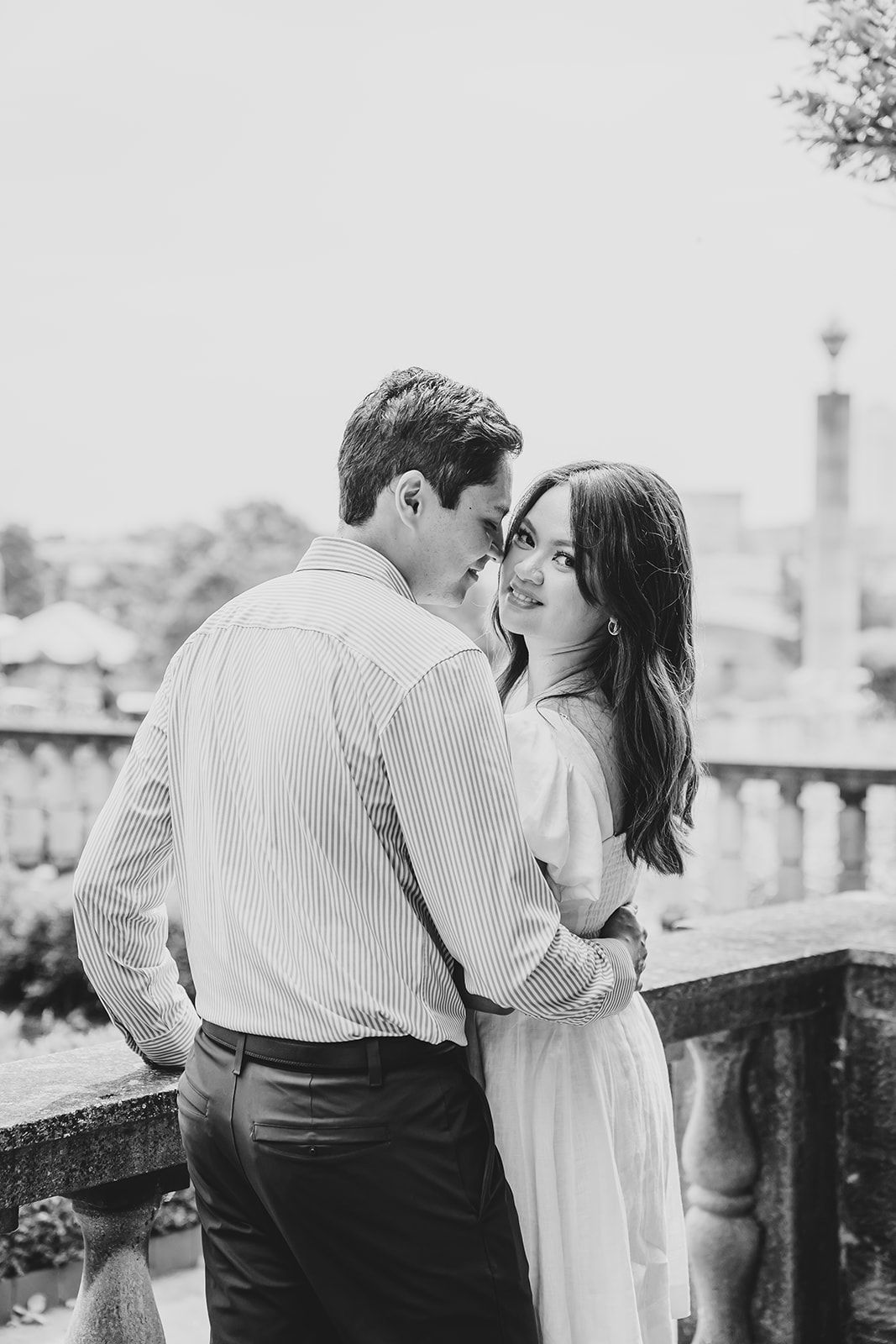Intimate moment captured in black and white as couple embraces on a balcony.