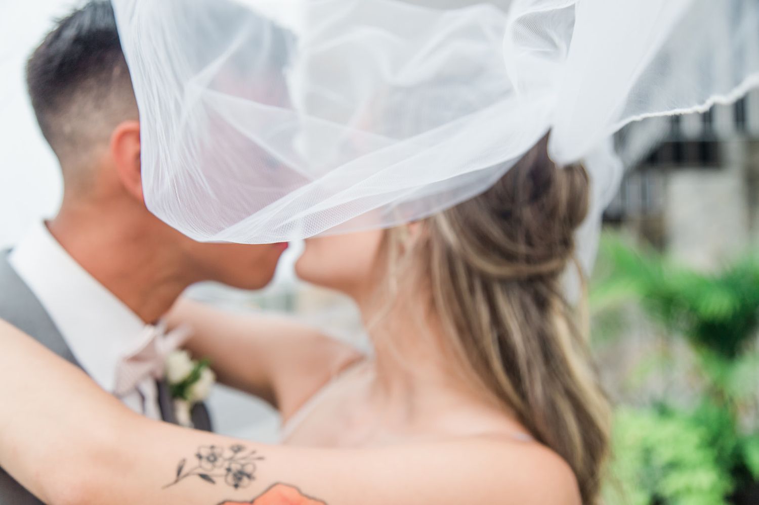 A romantic wedding moment shown through a delicate veil blowing in the breeze.