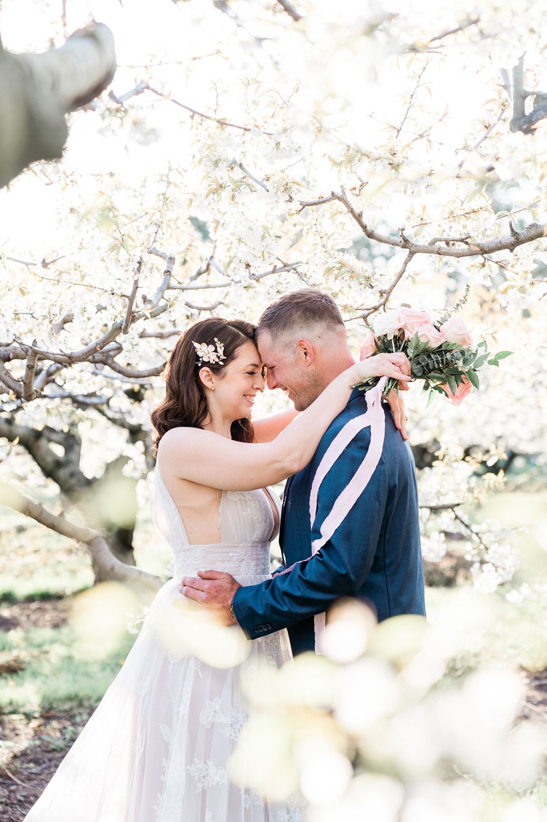 Romantic couple embracing under blooming cherry blossom trees in a spring garden setting.