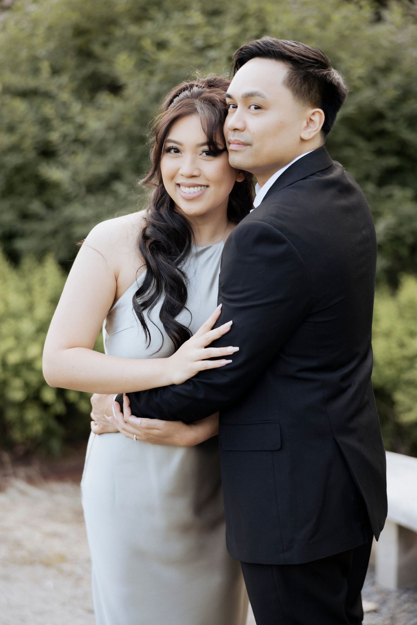A couple in formal attire embraces during an outdoor portrait session.