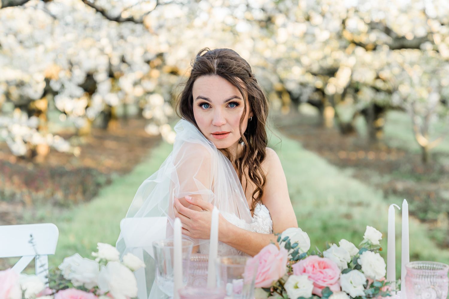 A bridal portrait with spring blossoms and pastel table decorations in an outdoor garden setting.