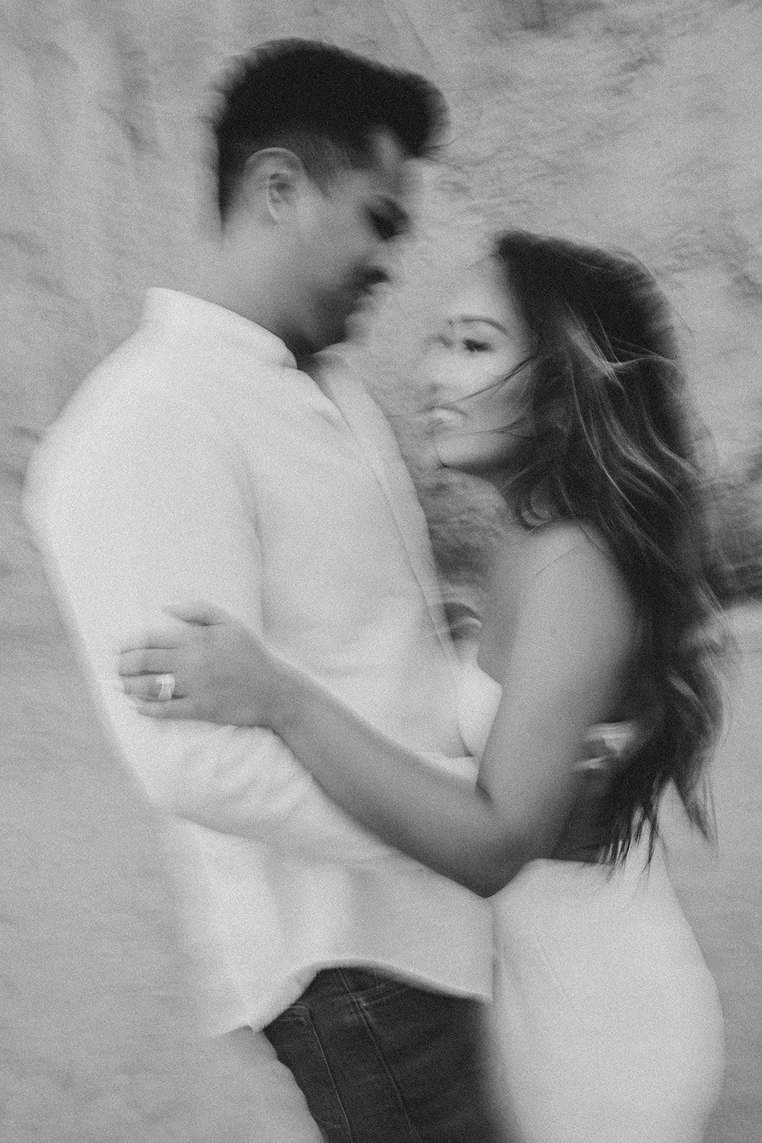 Artistic black and white portrait of couple in intimate embrace.