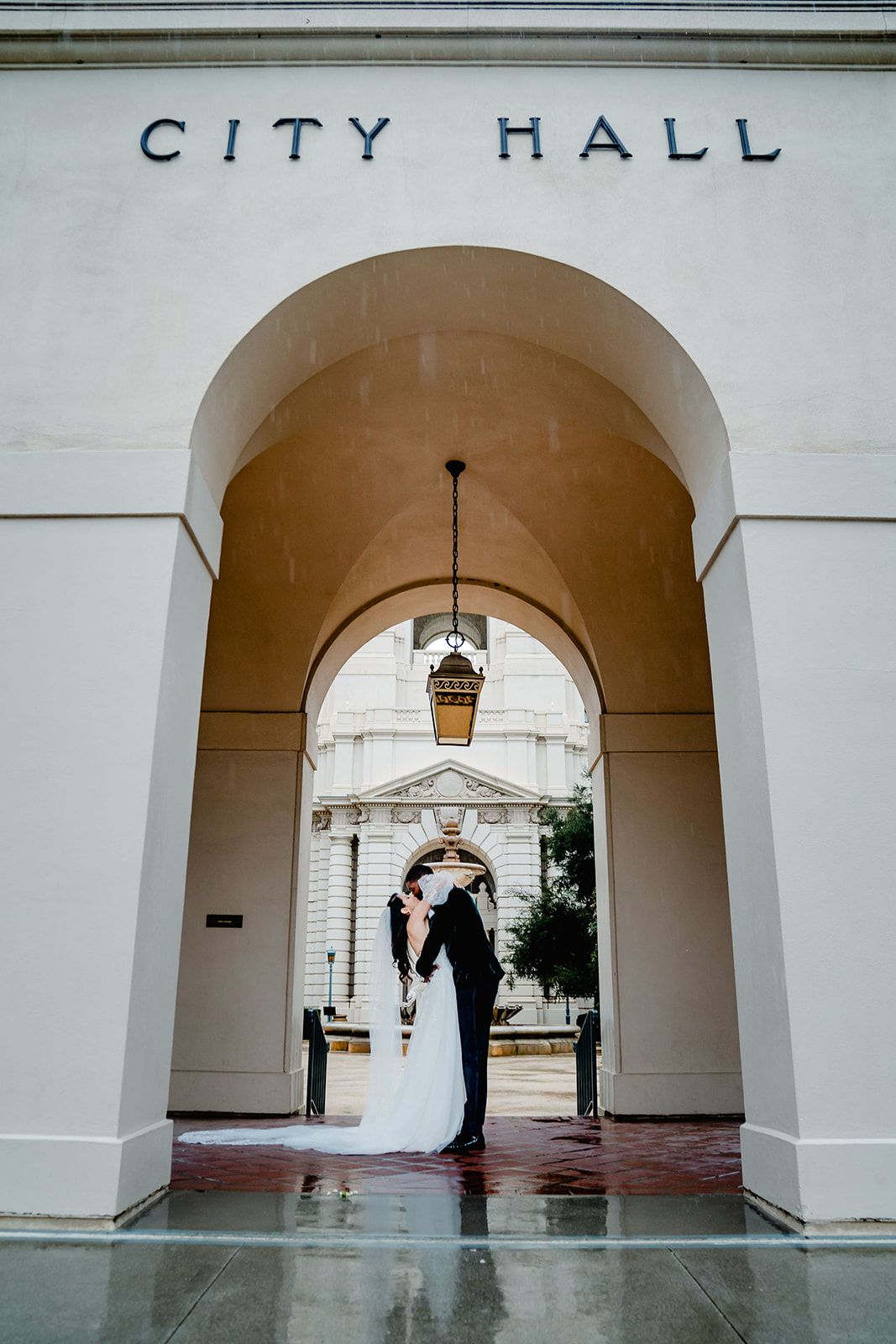 A couple stands under the arched entrance of City Hall during their wedding ceremony.
