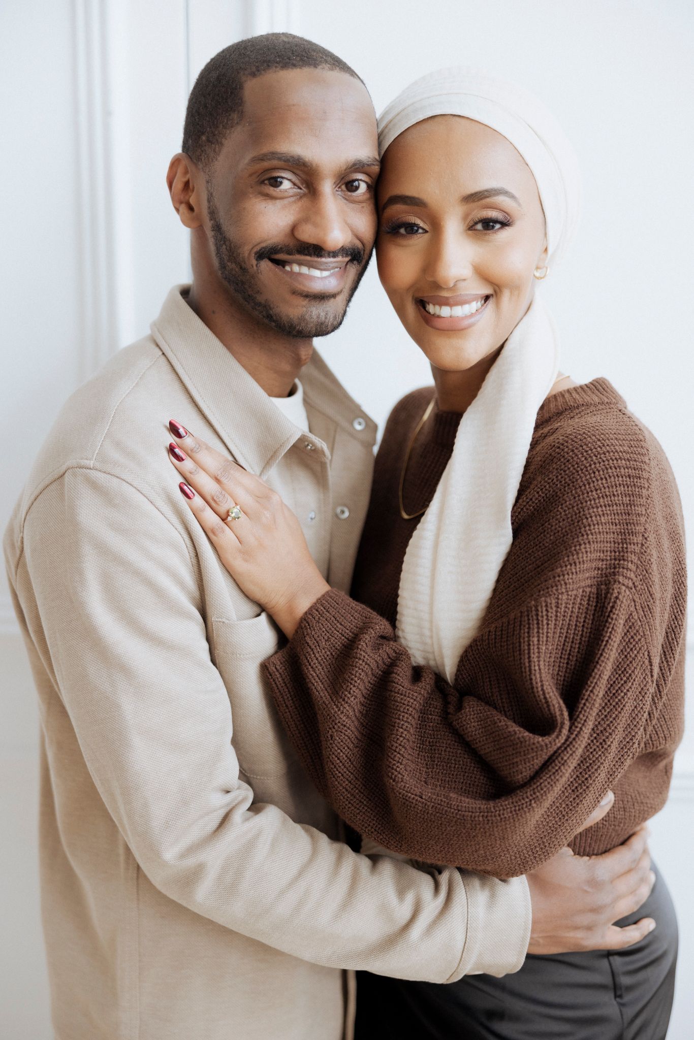 Close-up portrait of couple in cozy sweaters against white background.