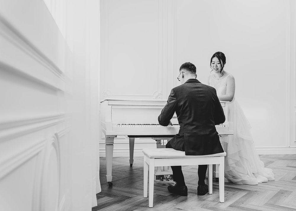 A romantic black and white photo series showing a couple seated at a white piano in minimalist setting.
