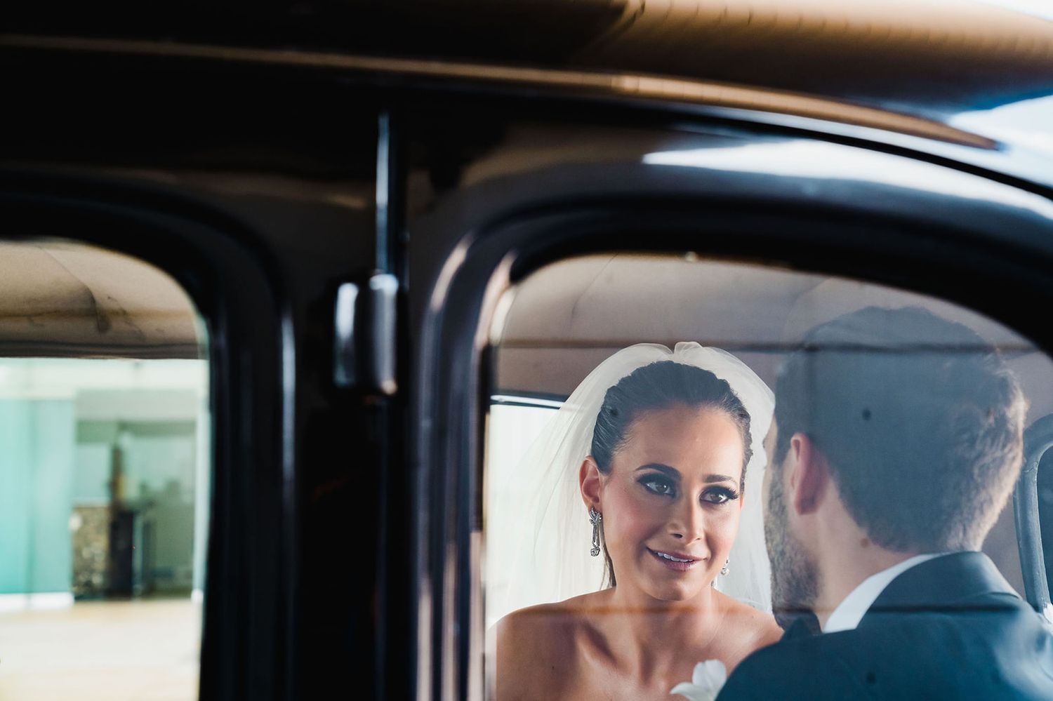 A couple shares a tender moment together inside a vintage car on their wedding day.