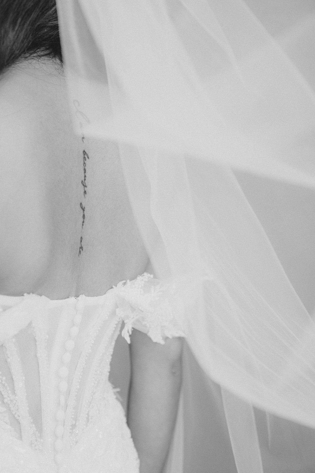 Close up black and white detail of delicate bridal veil and wedding dress bodice.