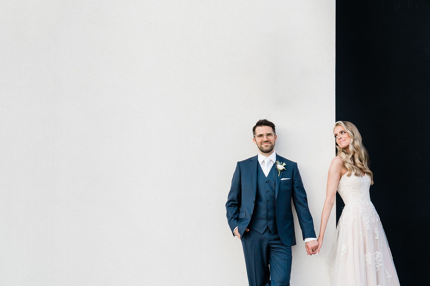 A couple in wedding attire poses dramatically against a black and white backdrop.