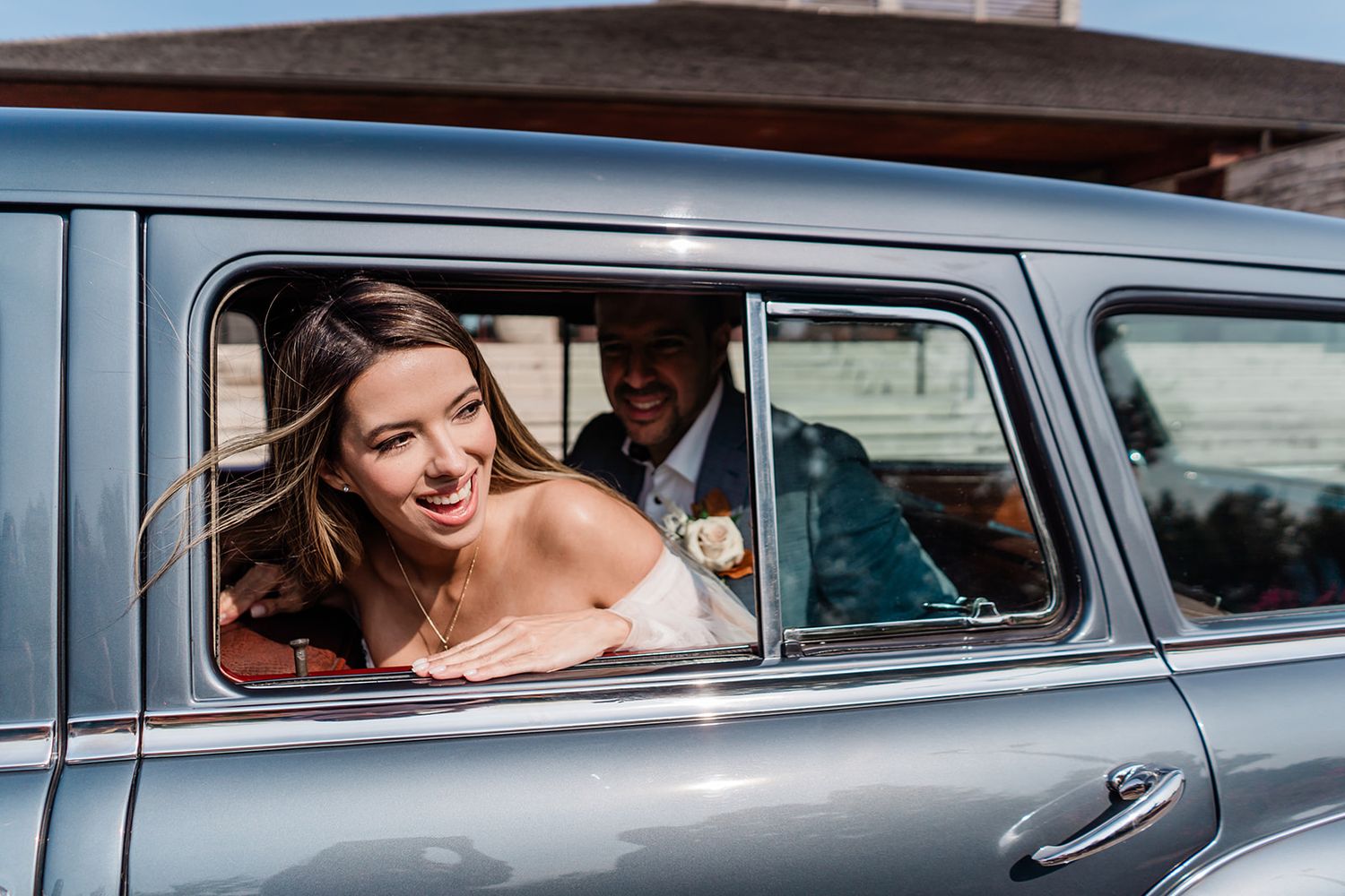 Vintage blue wedding car with joyful moment captured through window.