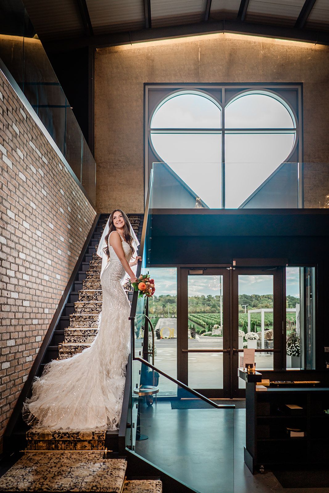 Interior of modern venue with large heart-shaped window and elegant staircase creating romantic architectural ambiance.