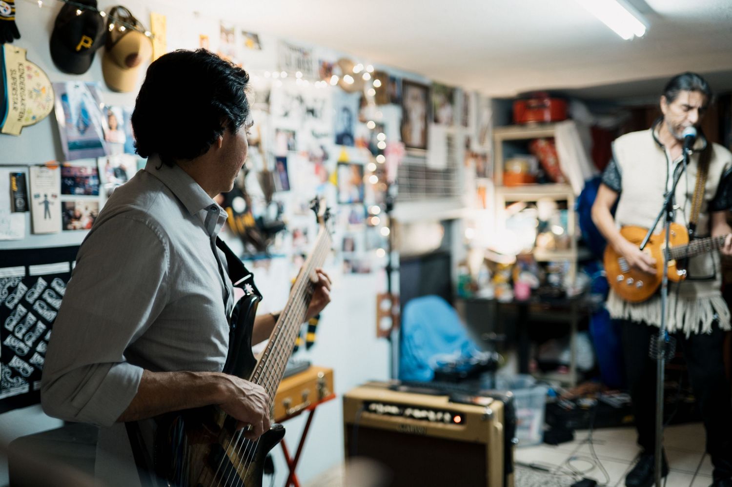Musicians performing in rehearsal space with guitars and equipment.