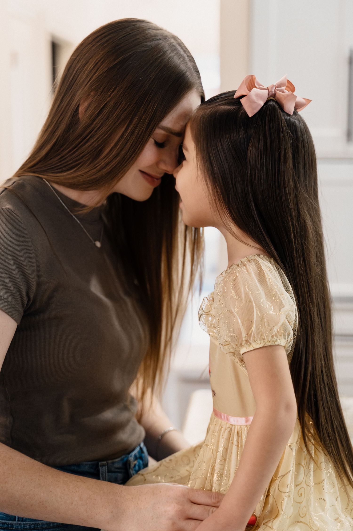 Tender moment between parent and child with matching long hair and gentle expressions.